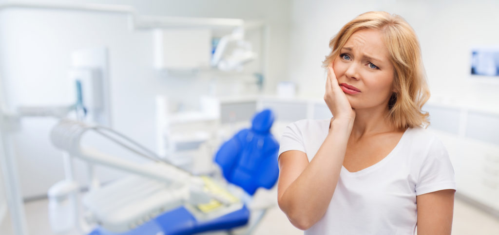 woman holding her jaw in pain