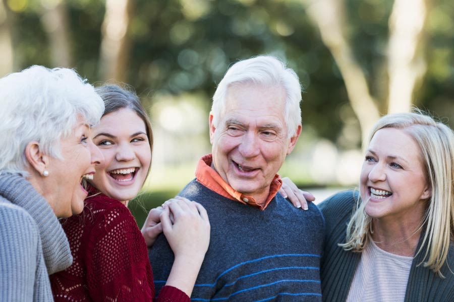 Two smiling grandparents talking to granddaughters.