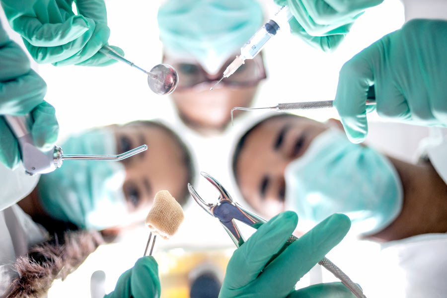 Masked dental professionals prepare for a wisdom tooth extraction.