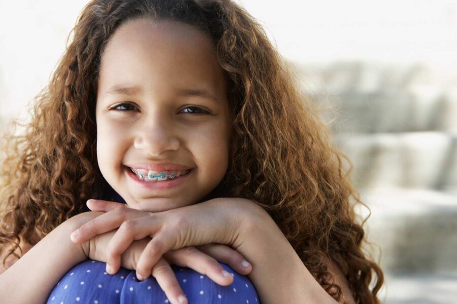 Curly-haired young girl with braces smiles while learning on her knees