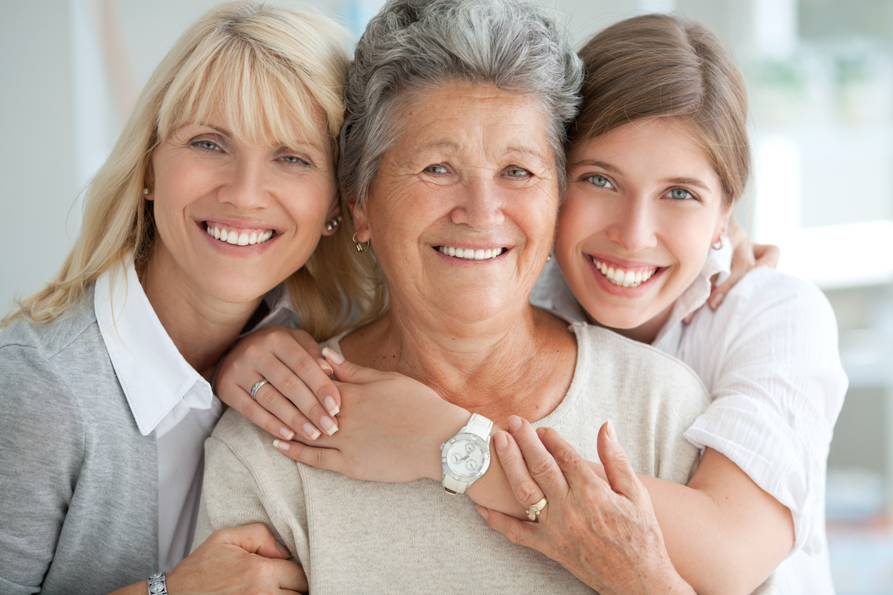Closeup of a gramma, mom, and daughter hugging and smiling together